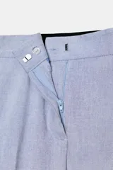 Pantalón tobillero celeste con tiro medio, cintura elástica en la espalda, bolsillos delanteros y falsos bolsillos de vivo en la espalda. Tiene aberturas laterales en el bajo y cierre frontal con cremallera, botón interior y gancho.