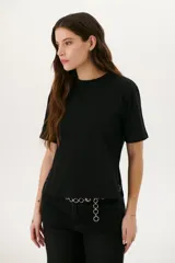 Remera blanca de algodón de corte recto, con cuello redondo y mangas cortas. Presenta detalle de aberturas laterales con ojales metálicos.