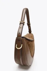 Bolso bandolera ovalado color verde oliva, con solapa de gamuza y asa de cuero ajustable.
