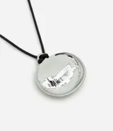 Collar corto para mujer con cordón negro y colgante de medalla circular robusta con acabado niquelado. Está fabricado con una mezcla de metales reciclados y cuenta con un diseño minimalista y moderno.