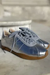 Zapatillas bajas con estampado animal print en blanco, marrón y negro, con puntera y talón en cuero color crema y suela de goma color caramelo.
