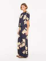 Remera azul marino con estampado de flores blancas y amarillas, de corte holgado, cuello redondo y mangas cortas.