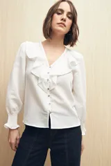 Camisa blanca a rayas verticales, con escote en V, mangas 3/4 con puños elastizados y volados.