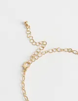 Collar dorado con cadena de eslabones y dijes colgantes: corazón con diseño floral, moño, perla y dije con forma de hoja.