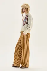 Pantalón de jean tiro medio, corte wide leg, con estampado de rayas verticales en tonos amarillo mostaza y marrón oscuro.