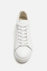 Zapatillas urbanas de cuero liso color blanco, con cordones y suela plana.