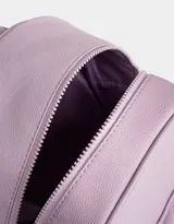 Mochila lila de cuerina con efecto acolchado y colgante de mariposa. Tiene correas regulables, manija superior, acceso con cierre superior y bolsillo frontal con cierre y tirador de goma en forma de mariposa.