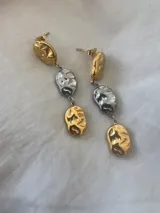 Aros colgantes con tres bolitas irregulares, dos doradas y una plateada.