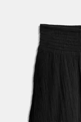 Falda larga negra de tiro alto con volantes en el mismo tejido.