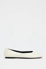 Zapato plano tipo bailarina de piel color crema con efecto craquelado y punta cuadrada abierta.