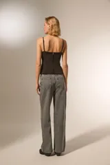 Pantalón gris de denim con corte recto, tiro alto y apliques de tachas cuadradas plateadas en los laterales.