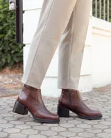 Botinetas de cuero color chocolate, con diseño de textura tipo reptil en el empeine y laterales. Presentan un taco cuadrado de altura media, suela de goma negra y cierre lateral para mayor comodidad.