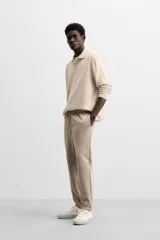Pantalón negro de corte cropped, con cintura elástica ajustable con cordón, bolsillos laterales y traseros de vivo. El bajo tiene terminación con vuelta.