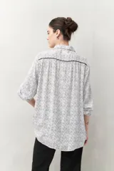 Camisa de manga larga con estampado paisley en tonos azul y blanco, cuello camisero y cierre frontal con botones.