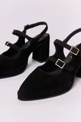 Zapato de cuero marrón con taco bloque, punta fina y dos tiras con hebillas doradas.