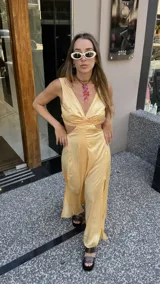 Vestido largo color durazno con escote pronunciado en V y aberturas laterales en la cintura. Presenta un drapeado frontal y falda con tajo lateral.