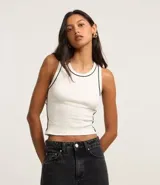 Musculosa blanca de rib con cuello redondo y frisos contrastantes en negro en el cuello y las sisas.