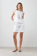 Blusa blanca sin mangas de lino con cuello redondo y volados en los hombros.