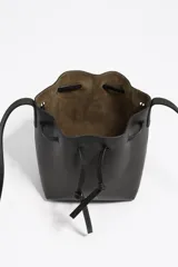 Bolso tipo bucket pequeño de piel vacuna, color marrón, con estructura blanda. Cuenta con asa regulable de piel y cierre de cordón ajustable. Presenta el logo metálico de BIMBA Y LOLA en dorado.