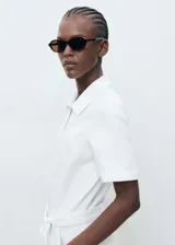 Mono largo blanco de algodón con cuello camisero, manga corta, cierre frontal con cremallera, cinturón desmontable y bolsillos laterales.