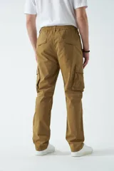 Pantalón cargo color beige, con cintura elástica ajustable con cordón, bolsillos laterales con cierre y bolsillos cargo con solapa.