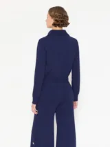 Saco azul tejido en hilado frío con punto cerrado y estructura pesada. Tiene acceso frontal con botones dorados y mangas largas.