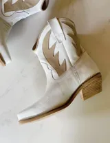 Botas cortas negras de cuero con bordados blancos estilo cowboy.