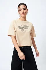 Remera cropped blanca de mangas ranglan con estampa frontal de un auto antiguo y texto "Vintage Gems / retro car club".