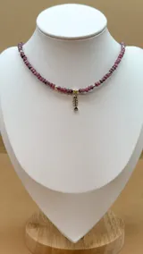 Collar de cinco hilos de cuentas facetadas de jade de Malasia color borgoña, con cuentas doradas y dijes colgantes dorados con incrustaciones de strass: estrella, espiral, mano de Fátima, luna creciente y esqueleto de pez.