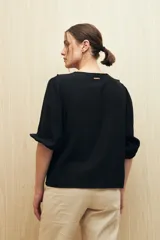 Blusa negra con mangas 3/4 y escote en V con volados.