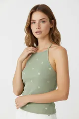 Musculosa verde con estampado de estrellas, breteles finos, corte al cuerpo y cuello redondo.