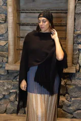 Ruana color crudo tejida a mano en punto arroz con lana merino. Presenta flecos en el borde inferior.