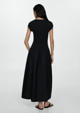 Vestido midi verde oliva con corte a la cintura y falda amplia. El cuerpo es de tejido de punto ajustado y la falda es de algodón. Tiene mangas cortas y cuello redondo.