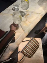 Bolso tipo bandolera, tejido en cuero color bordó, amarillo y blanco.