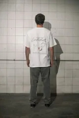 Remera blanca de algodón con cuello redondo y estampado con la frase "Good for nothing new collection est. 2001 el pinar city" y un pato con una botella de alcohol.
