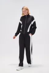 Pantalón de jogging negro con cintura elástica, corte holgado y una franja vertical blanca a lo largo de la pierna.