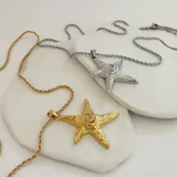 Collar dorado con cadena de eslabones retorcidos y dije de estrella de mar con diseño de espiral en el centro.