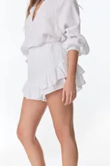 Short pollera blanco de tela arrugada con volados y detalles de encaje.
