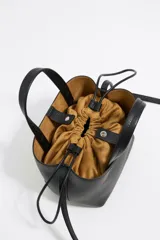 Bolso tote pequeño color visón de piel granulada con doble asa corta y correa bandolera ajustable y extraíble. Incluye bolsa interior ajustable con cordones. Logotipo de la marca grabado en el frente.