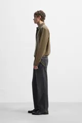 Camisa negra relaxed fit confeccionada en tejido fluido con mezcla de viscosa. Tiene cuello solapa, manga larga con puño abotonado y cierre frontal con botones.
