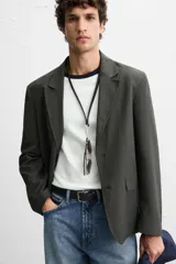 Blazer regular fit color gris oscuro, confeccionada en tejido con estructura. Cuello con solapas de muesca y manga larga. Bolsillos de solapa en cadera. Cierre frontal de botonadura.
