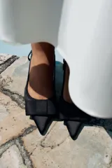 Zapato destalonado negro con tacón ancho y tira trasera. Detalle de lazo en la parte delantera.
