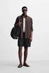 Bermuda regular fit negra confeccionada en tejido de lino. Cintura elástica ajustable con cordón y pliegues frontales. Bolsillos frontales y detalle de bolsillos traseros de plastrón.
