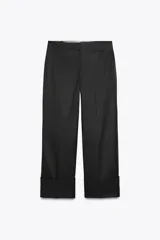 Pantalón de vestir negro de corte ancho, con tiro medio, trabillas en la cintura, raya planchada y dobladillo ancho.