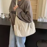 Bolso hobo color bordó de tela suave, liviana y espaciosa, con bolsillos frontales con cierre y correa ajustable.