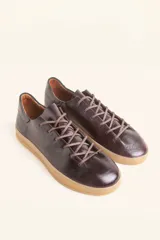 Zapatilla de cuero vacuno color azul marino, con cordones azules y suela de caucho color caramelo.