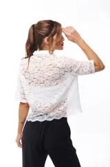 Camisa blanca de encaje con cuello clásico, cierre frontal con botones y mangas cortas.
