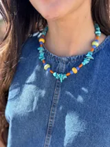 Collar corto con piedras turquesas irregulares, cuentas de cerámica amarillas y verdes, y cuentas plásticas naranjas y azules.