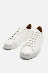 Zapatillas blancas de cuero sintético con cordones, forro interior y plantilla color beige.