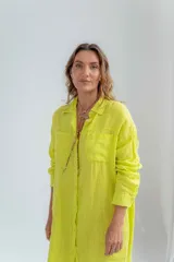 Vestido camisero color verde lima de lino, con cuello clásico, cierre frontal con botones y mangas largas con puños abotonados.